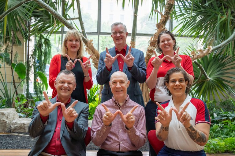 A group of UW-Madison administrative staff hold up the Wisconsin "W."